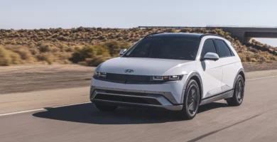 Coche blanco eléctrico en carretera desértica bajo cielo despejado.