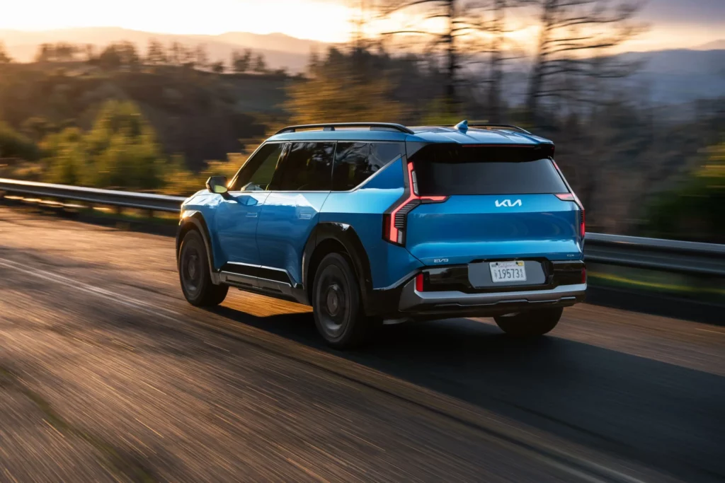 SUV azul conduciendo en una carretera al atardecer.