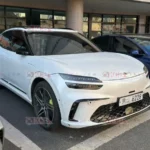 Coche blanco moderno estacionado en un aparcamiento exterior.