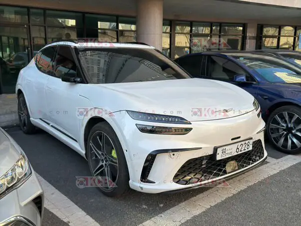 Coche blanco moderno estacionado en un aparcamiento exterior.