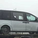 Una minivan gris sobre una plataforma de transporte.