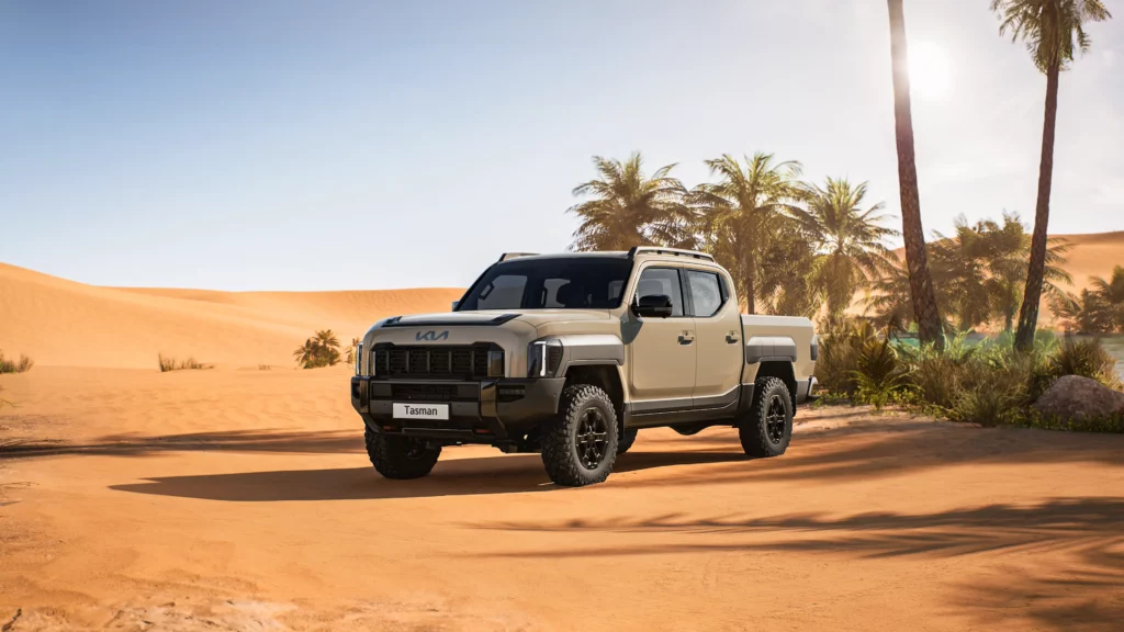 Camioneta Kia en el desierto bajo el sol y palmeras.