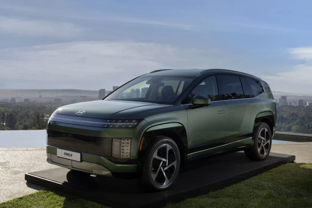 SUV verde metalizado en exhibición con paisaje urbano de fondo.