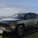 SUV verde metalizado en exhibición con paisaje urbano de fondo.