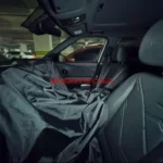 Interior de un coche aparcado, cubierto parcialmente por tela negra.